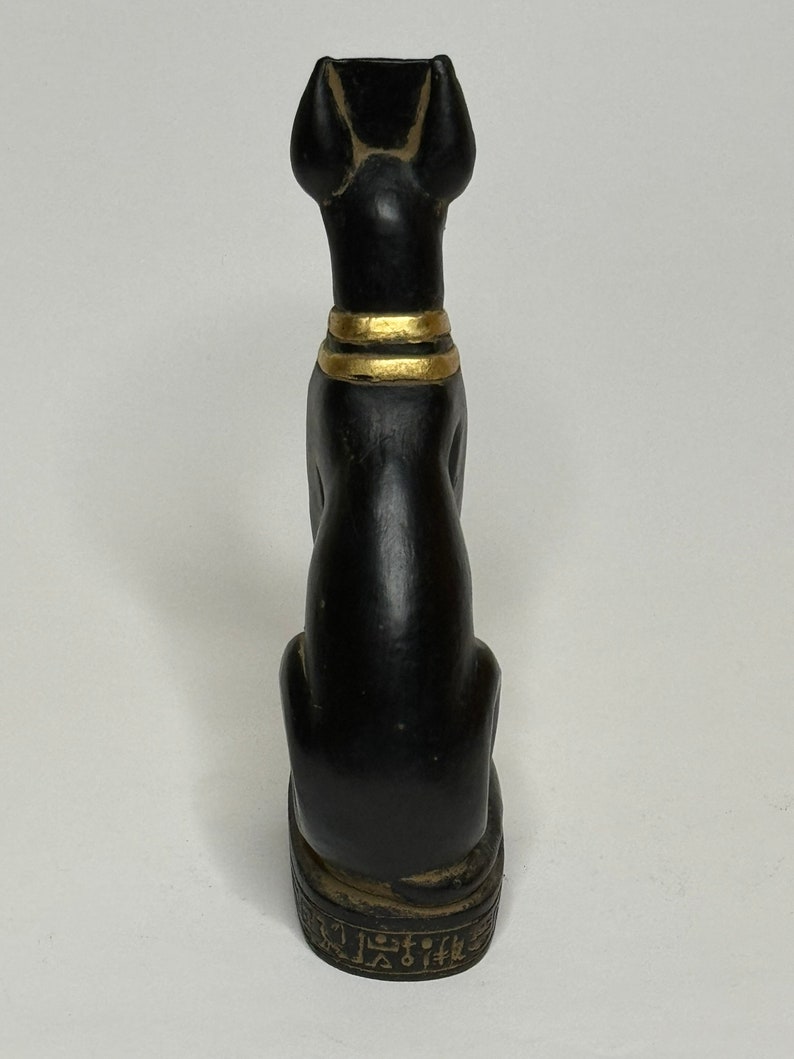 May include: Black ceramic statue of the Egyptian goddess Bastet, a cat with gold accents and hieroglyphics on the base.