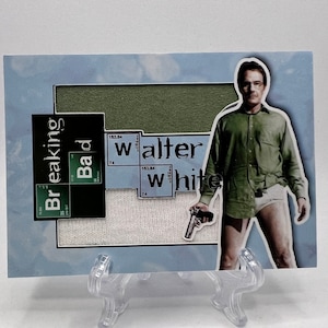 May include: A Breaking Bad trading card featuring Walter White, a character from the TV show. The card has a blue background with a white and green design. The text "Breaking Bad" and "Walter White" is visible on the card.