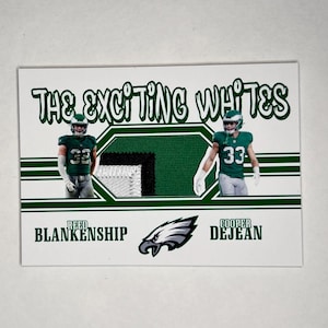 May include: A trading card featuring two football players in green and white uniforms. The card has the text "THE EXCITING WHITES" at the top, with the team logo and player names "REED BLANKENSHIP" and "COOPER DEJEAN" at the bottom.