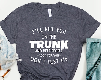 May include: A dark heather gray t-shirt with white text that reads "I'll put you in the trunk and help people look for you. Don't test me."