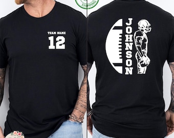 May include: Black t-shirt with white text and graphics. The front features "TEAM NAME" above the number "12". The back displays a football graphic with the name "JOHNSON" and a football player silhouette. A "Next Day Shipping" logo is visible.