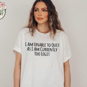 May include: White t-shirt with black text that reads "I am unable to quit as I am currently too legit."