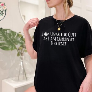 May include: Black t-shirt with white text that reads "I am unable to quit as I am currently too legit".