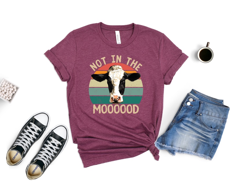 May include: A maroon t-shirt with a vintage-style graphic of a cow's head with the text "Not in the Mooooood".
