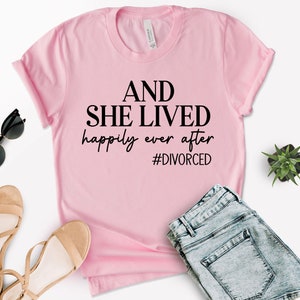Puede incluir: Camiseta rosa con el texto "AND SHE LIVED happily ever after #DIVORCED" en negro.