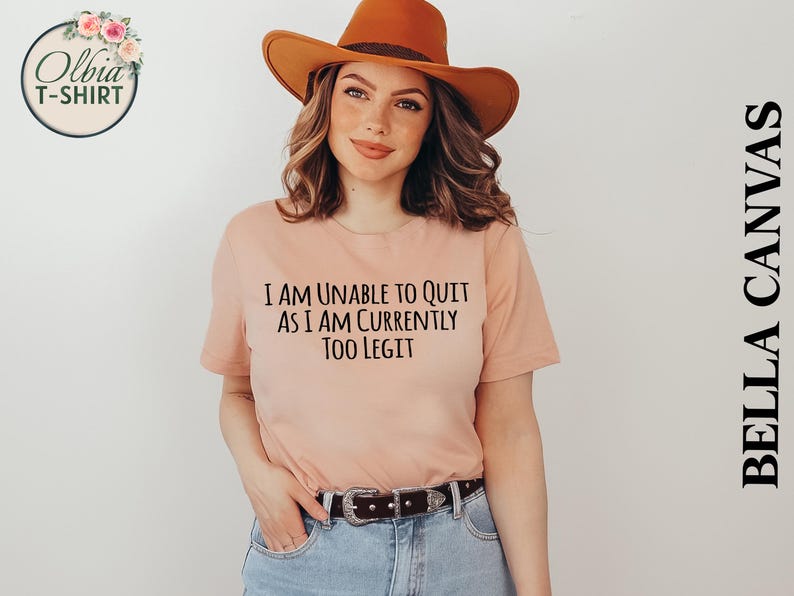 May include: A peach-colored t-shirt with the text "I am unable to quit as I am currently too legit" printed in black.