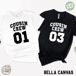 K&ouml;nnte beinhalten: Zwei Bella Canvas T-Shirts, eines wei&szlig; und eines schwarz, mit dem Text "COUSIN CREW" und den Zahlen 01 und 03 in fett, bzw. schwarz und wei&szlig;. Das wei&szlig;e Shirt ist unten geknotet. Das Bild enth&auml;lt ein "Next Day Shipping"-Abzeichen.