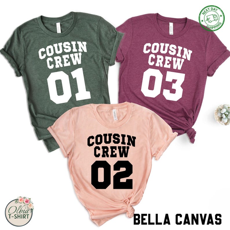 K&ouml;nnte beinhalten: Drei kurz&auml;rmelige T-Shirts in Gr&uuml;n, Burgunderrot und Pfirsich. Jedes Shirt hat die Aufschrift "COUSIN CREW" &uuml;ber einer Nummer: 01, 03 und 02. Der Markenname "BELLA CANVAS" ist unten rechts aufgedruckt.