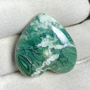 Peut inclure: Un cabochon d'agate vert et blanc en forme de cœur avec un motif tourbillonnant. La pierre a une finition polie et est prête à être sertie dans un bijou.