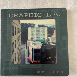 May include: A book titled "GRAPHIC L.A." with a cityscape photo on the cover. The cover is dark green with white text, including the author's name, Robh Ruppel. The photo shows buildings and a view of the city.