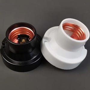 May include: Two light bulb sockets, one black and one white, with copper-coloured contact points. The sockets are designed for standard light bulbs.