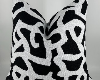 May include: Black and white patterned throw pillow with an abstract design. The pillow is made of a soft, textured fabric.