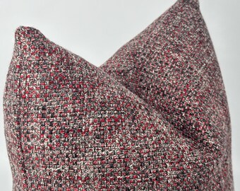 May include: A square throw pillow featuring a textured, woven fabric with a multi-colored pattern of deep red, black, and white threads. The material has a distinct cross-hatch appearance with a dense, heavy-duty weave and a soft, plush shape.