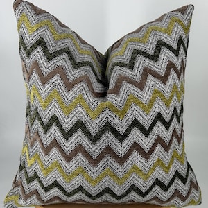 May include: A decorative pillow with a chevron pattern in shades of brown, green, and yellow.