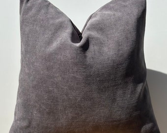 May include: A dark gray throw pillow with a soft, textured fabric. The pillow is square shaped and has a simple design.