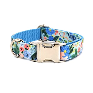 Op de afbeelding: Een blauwe hondenriem met een bloemenpatroon en een zilveren gesp.