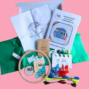 May include: An embroidery kit to create Oscar Piastri's 2024 Formula 1 helmet. The kit includes a hoop, embroidery floss, a needle, a pattern, and instructions. The kit is packaged in a box with green tissue paper wrapping.