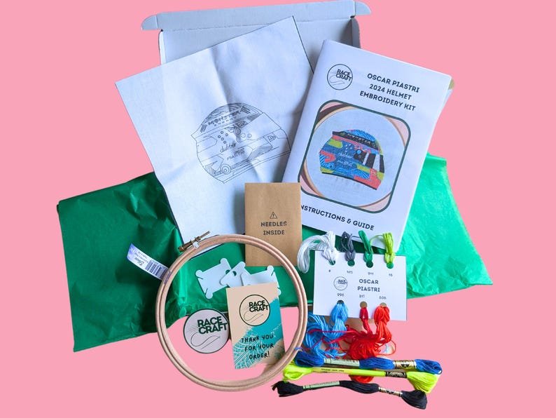 May include: An embroidery kit to create Oscar Piastri's 2024 Formula 1 helmet. The kit includes a hoop, embroidery floss, a needle, a pattern, and instructions. The kit is packaged in a box with green tissue paper wrapping.