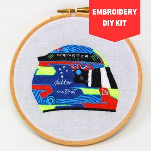May include: Embroidered racing helmet DIY kit featuring a blue, green, red, and white design with the text "Monster Energy" and "Oscar Piastri" on the helmet.