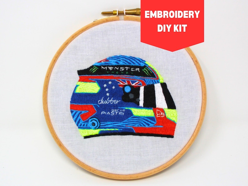 May include: Embroidered racing helmet DIY kit featuring a blue, green, red, and white design with the text "Monster Energy" and "Oscar Piastri" on the helmet.