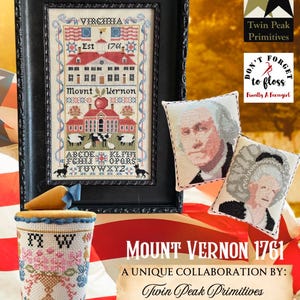 Könnte beinhalten: Ein gerahmtes Stickmuster von Mount Vernon, dem Haus von George Washington, mit dem Text "Virginia Est 1761 Mount Vernon". Das Muster ist von einem schwarzen Rahmen umgeben. Das Bild enthält auch ein kleines Kissen mit einem Stickbild von George Washington, ein kleines Kissen mit einem Stickbild von Martha Washington und einen kleinen zylindrischen Behälter mit einem Stickmuster eines Blumenarrangements. Das Bild ist vor einem rot-weiß-blauen amerikanischen Flaggenhintergrund platziert. Der Text "Twin Peak Primitives" und "Finally A Farm Girl" ist ebenfalls im Bild enthalten.