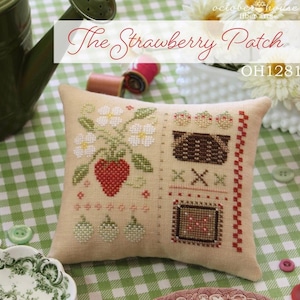 May include: A beige cushion with a cross-stitch design of a strawberry patch, flowers, and a basket of strawberries. The cushion is on a green and white checked fabric. The text "The Strawberry Patch" and "OH1281" are visible on the image.