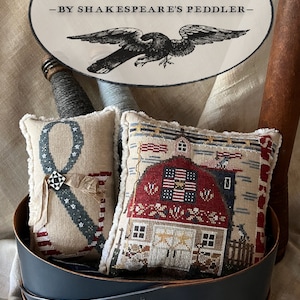 May include: Two embroidered pillow covers with a patriotic theme. The first pillow features a blue and white ribbon with stars and the second pillow features a red barn with a flag and stars. The pillows are in a blue and brown wooden basket. The text on the image reads "& STRIPES -BY SHAKESPEARE'S PEDDLER- Companion to "Stars" by Plum Street Samplers"