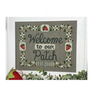 May include: A cross-stitch embroidery design featuring a welcome sign with a strawberry border. The sign reads "Welcome to our Patch Est. 2000".