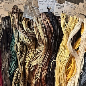 Könnte beinhalten: Sortiment von Stickgarnrollen in verschiedenen Farben, darunter Rot, Grün, Braun, Gelb und Grau. Die Rollen sind mit dem Markennamen "Weeks Dye Works" und der Farbnummer gekennzeichnet.
