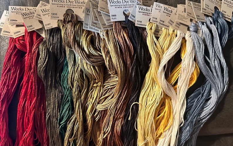 Pu&ograve; includere: Assortimento di rocchetti di filo da ricamo in vari colori, tra cui rosso, verde, marrone, giallo e grigio. I rocchetti sono etichettati con il nome del marchio "Weeks Dye Works" e il numero del colore.