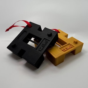 May include: Two weight plates, one black and one gold, with a red ribbon attached. Both plates are labelled "12.5KG".