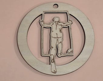 May include: A wooden ornament featuring a cutout of a human figure within a rectangular frame, set inside a circular frame. The figure is depicted in a running pose. The ornament has a hole at the top for hanging.