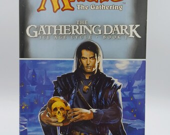 May include: A book cover for "The Gathering Dark", the first book in the Ice Age Cycle of Magic: The Gathering novels. The cover features a man in a dark jacket holding a golden skull. The text on the cover reads "Magic: The Gathering", "The Gathering Dark", "Ice Age Cycle - Book I", and "Jeff Grubb".