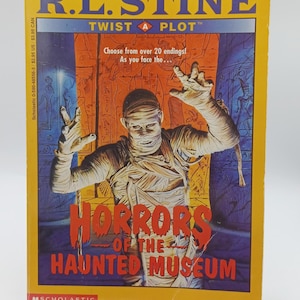 May include: A paperback book titled "Horrors of the Haunted Museum" by R.L. Stine. The cover features a mummy with outstretched arms against a backdrop of an Egyptian-style tomb. The book is part of the "Twist a Plot" series.