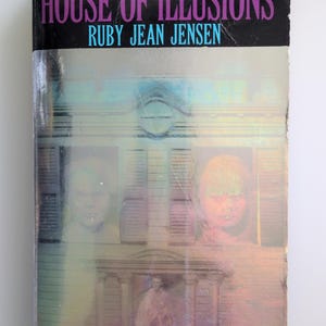 May include: A paperback book titled House of Illusions by Ruby Jean Jensen. The cover features a dark, eerie house with two ghostly faces appearing in the windows and a figure standing in the doorway, with the text THEY MADE THE CHILDREN LAUGH—AND SHRIEK.