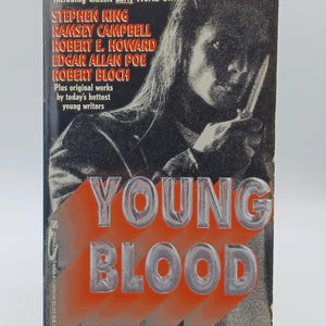 May include: A paperback book titled "Young Blood" with a cover featuring a shadowy figure holding a knife. The cover also includes the names of authors like Stephen King and Edgar Allan Poe. The title is in large, silver letters.