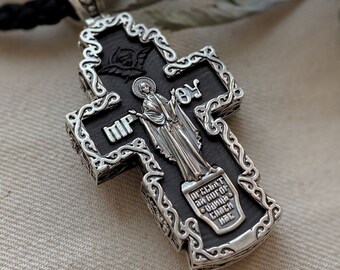 May include: A silver and black cross pendant with intricate detailing. The cross features a depiction of the Virgin Mary and the inscription "MP OY".