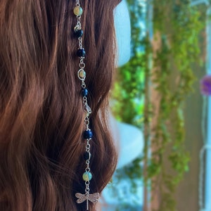 May include: A silver hair chain with black and light green beads and a dragonfly charm.
