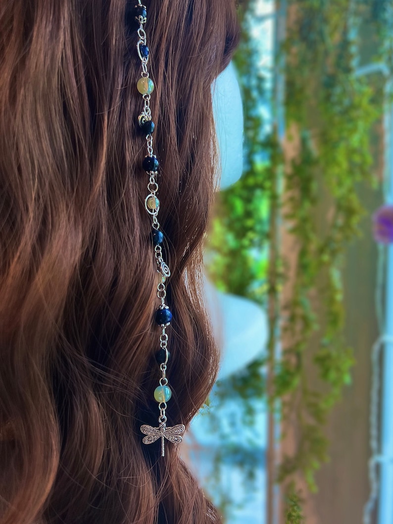 May include: A silver hair chain with black and light green beads and a dragonfly charm.