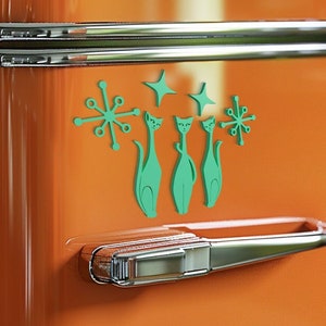 May include: A vintage orange refrigerator with three green cat magnets and starburst designs on the front. The refrigerator has two chrome handles.