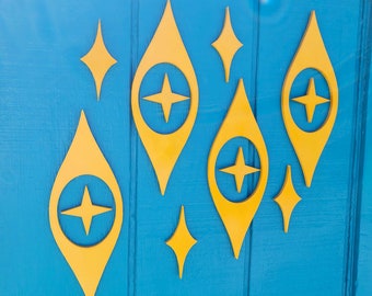 May include: A blue door decorated with yellow geometric shapes. The shapes are in the form of stars and teardrops with a star inside each teardrop.