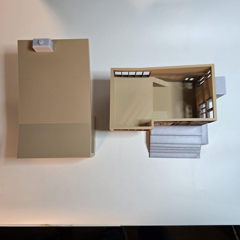 May include: A 3D printed model of a house with a flat roof and a set of stairs leading up to the front door. The house is made of beige plastic and has a light gray roof.