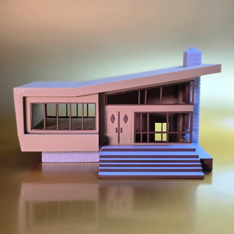 May include: A beige model home with a slanted roof, large windows, and a set of steps leading to the front door. The model home has a chimney on the roof.