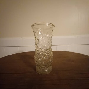 May include: A clear glass vase with a textured surface. The vase has a wide mouth and a narrow base.