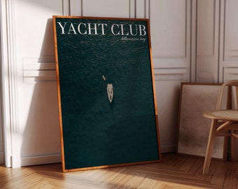 Peut inclure: Une affiche encadrée avec le texte "YACHT CLUB Billionaires Bay" en lettres blanches sur un fond bleu foncé. L'affiche présente une vue aérienne d'un yacht blanc sur l'eau.