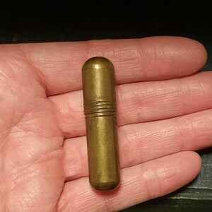以下が含まれることがあります： 丸みを帯びたトップとわずかにテクスチャ加工された表面を持つ金色の金属製の指ぬき。指ぬきは、中央に水平な溝がいくつかあります。