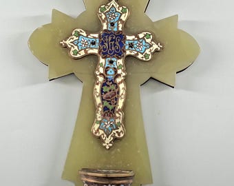 May include: A decorative cross with a light green background and a smaller, ornate cross in the center. The central cross features blue, white, and gold enamel detailing. A small, decorative bowl is at the bottom of the cross.