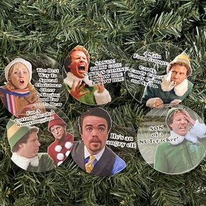 May include: Six round, clear, plastic ornaments with images of Buddy the Elf from the movie Elf. Each ornament has a different quote from the movie. The quotes are: "The Best Way To Spread Christmas Cheer Is Singing Loud For All To Hear", "I'm A Cottong Headed Ninnymuggins", "SANTA! OH MY GOD! SANTA'S COMING! I KNOW HIM! I KNOW HIM", "4 Main Food Groups: Candy, Candy Canes, Candy Corns, and Syrup", "He's an angry elf", "SON of a NUTcracker!"