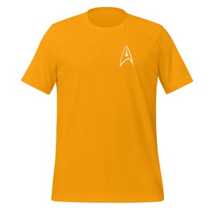 Op de afbeelding: Een geel T-shirt met korte mouwen en een wit Starfleet-insigne op de linkerborst.
