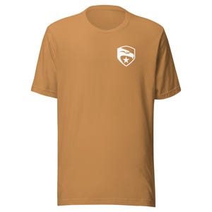 May include: A tan short-sleeved t-shirt with a white eagle logo on the left chest. The logo is a shield with a star and an eagle inside.